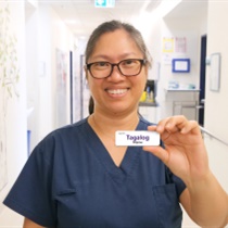 Austin Health staff member holding up Tagalog language badge as part of the Language Skills Badge Program